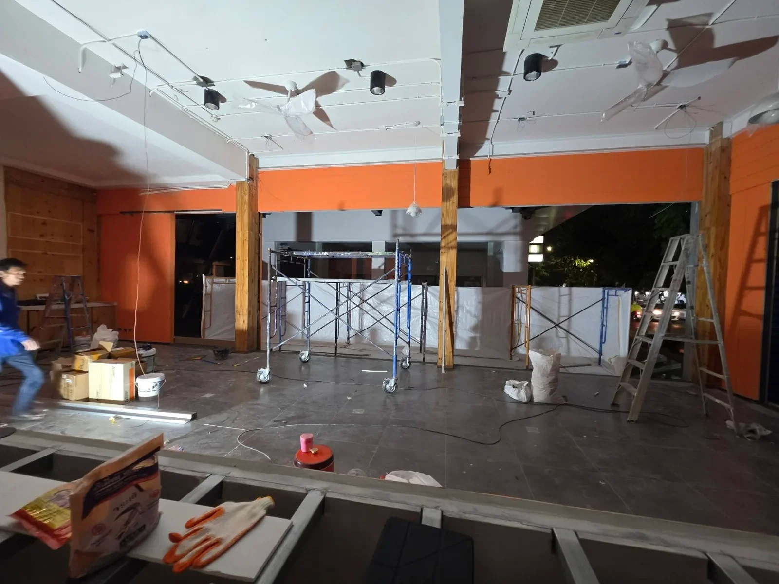 ภายในร้านช่วงเข้างานกลางคืน เห็นงานฝ้า งานไฟราง และผนังสีส้มที่ทาเสร็จแล้ว