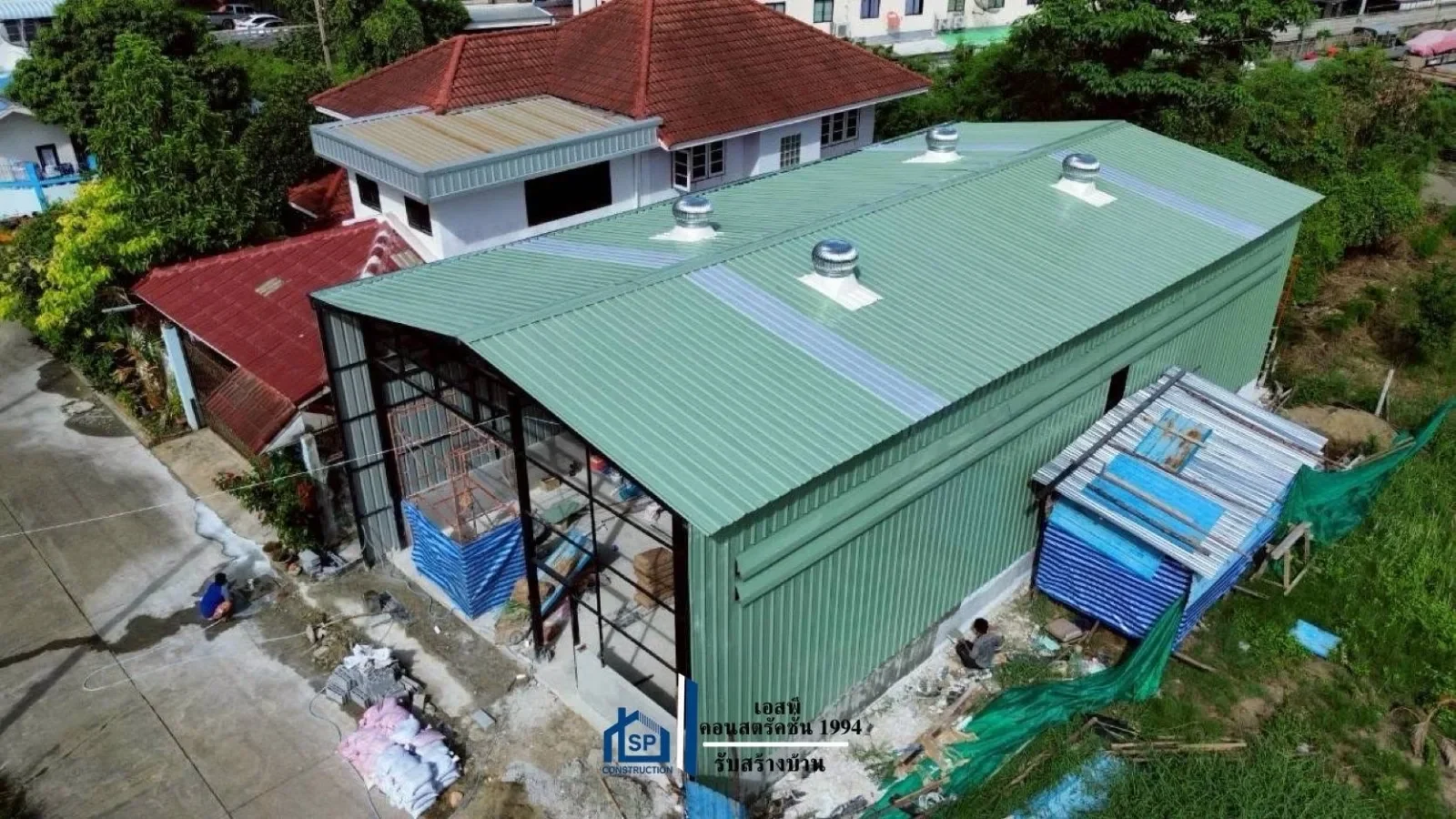 ภาพมุมสูงของงานก่อสร้างที่แล้วเสร็จ เห็นอาคารใหม่คู่กับบ้านพักเดิม